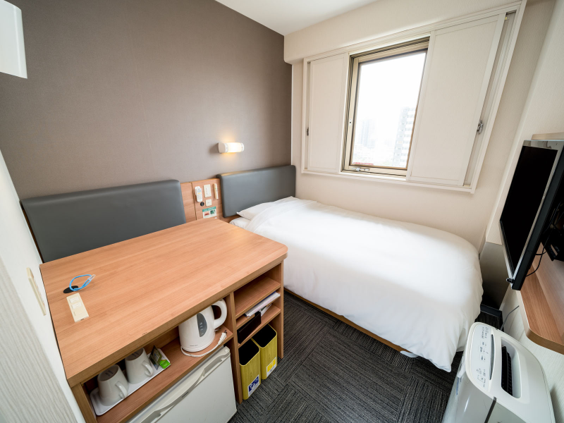 A 12 m² Standard room at Super Hotel Anjo Station Front: a bed along the window wall, a desk unit with kettle and cups beside it, and a narrow strip of carpet.