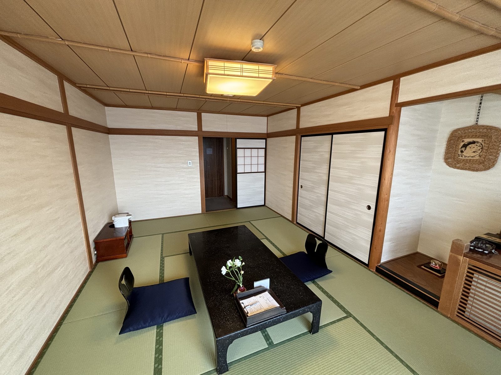 A tatami room with a low black table, two floor cushions and no Western bed anywhere in the room.