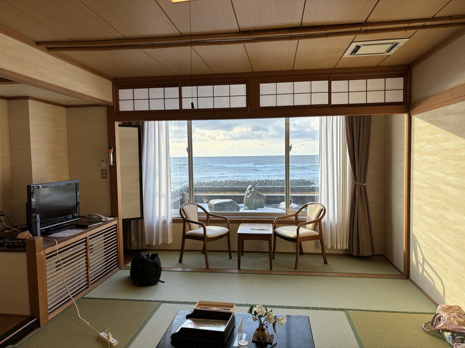 A tatami guest room with a low table, floor cushions and a wide window, and no bed anywhere in it.