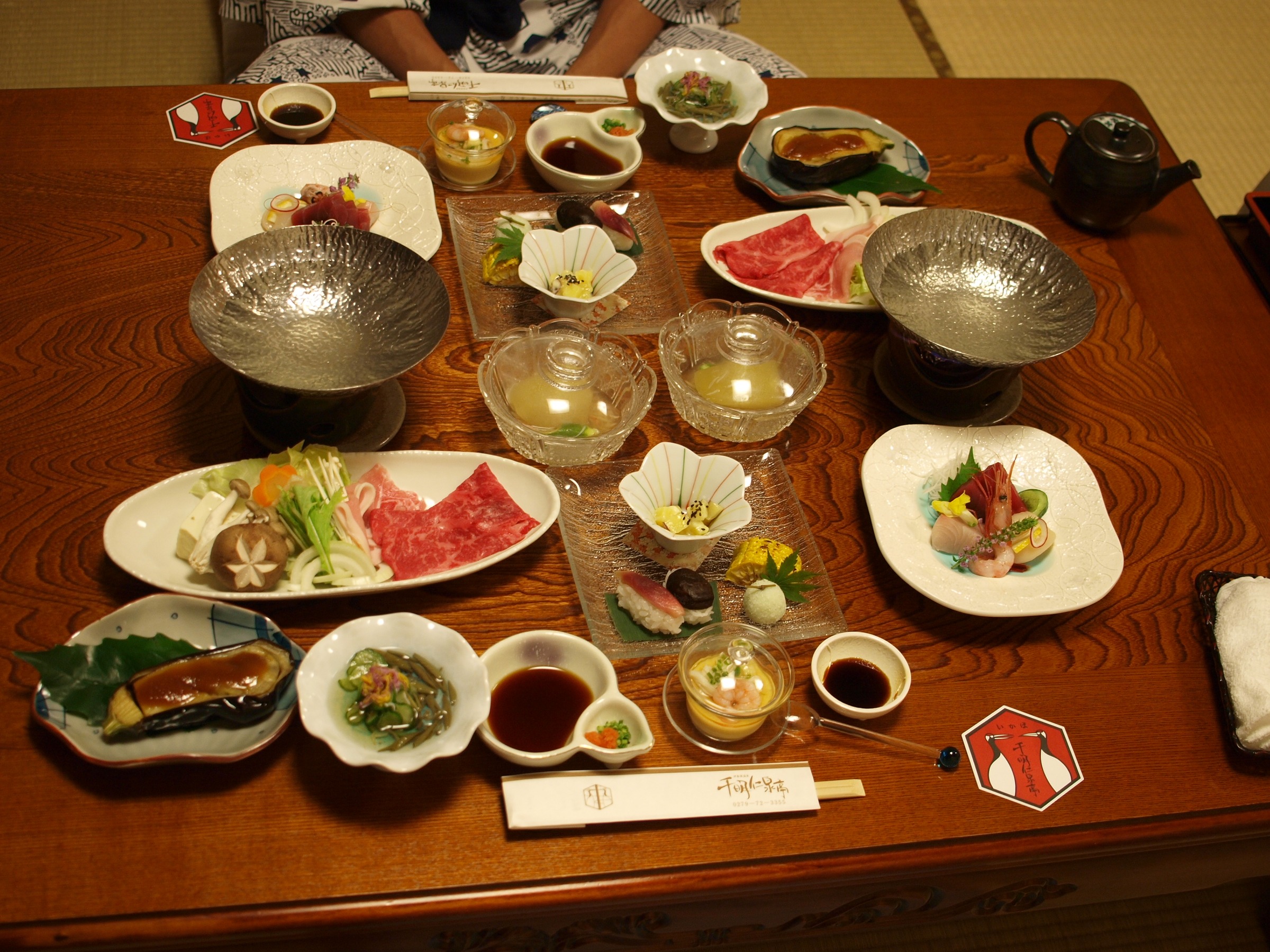 A ryokan dinner laid out on a low wooden table on tatami: sashimi, hot-pot ingredients and small dishes.